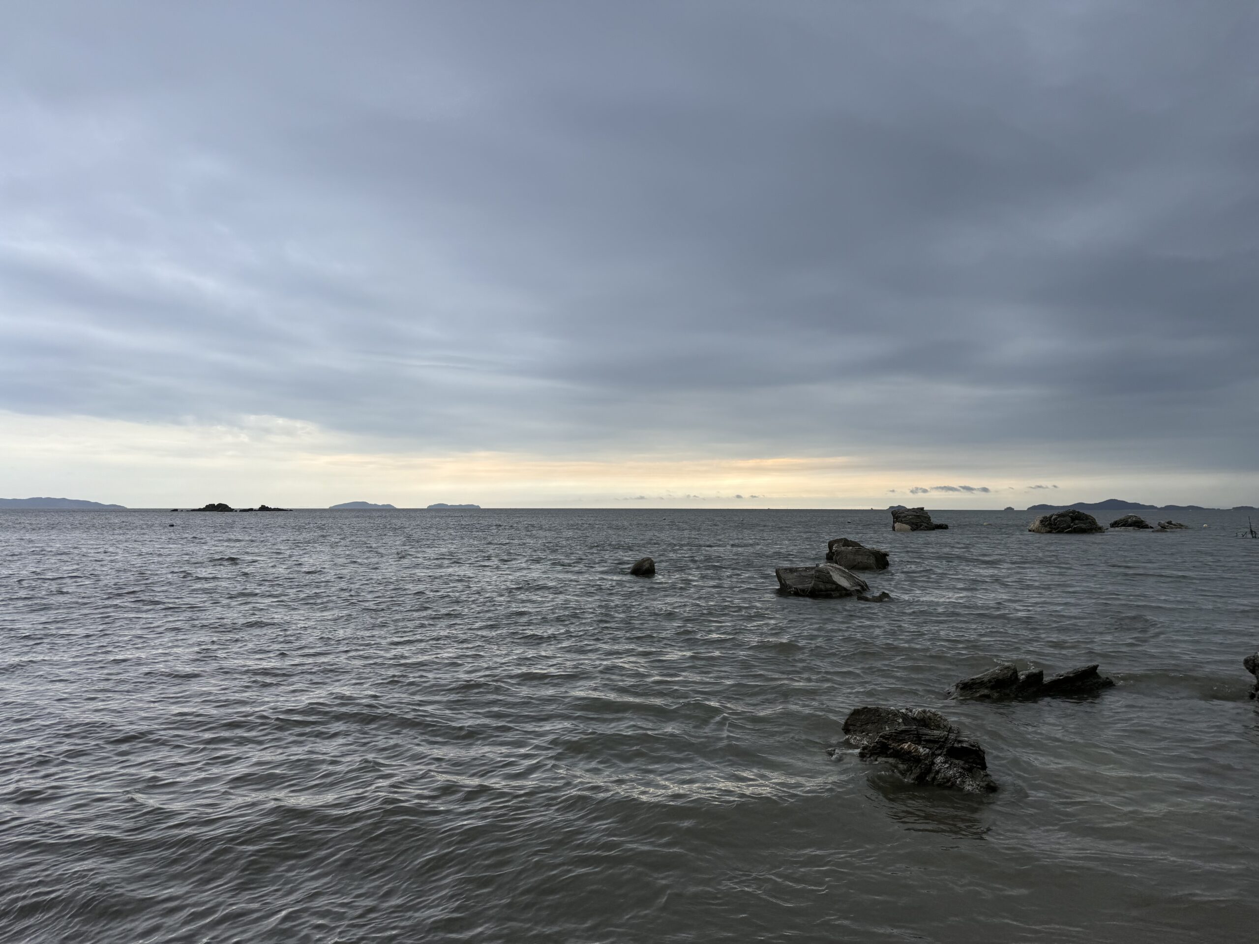 View of Anmok Beach in Incheon with calm waves under a cloudy sky during sunset