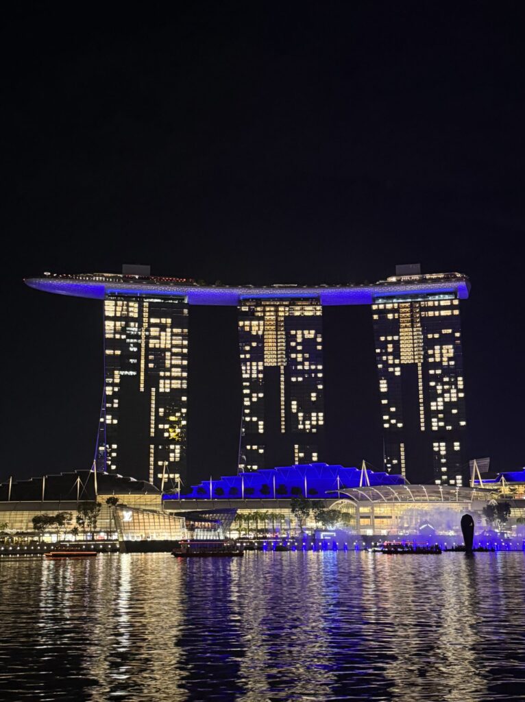 A night view of the Marina Bay Sands hotel in Singapore, with its unique rooftop structure and illuminated windows.