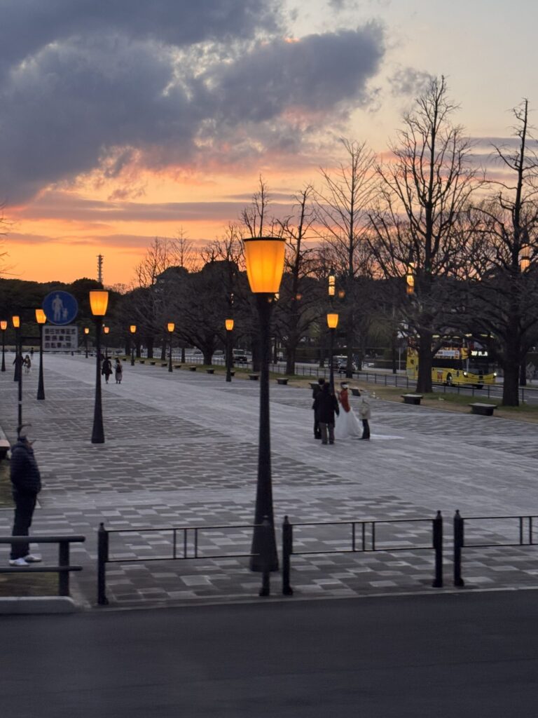 Tokyo Station Plaza at Sunset, Japan — Street lamps glow warmly as the sky turns shades of orange and pink.