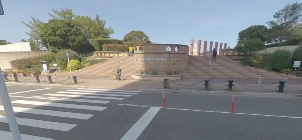 A scenic outdoor location with large stone steps leading up to a structure, set against a clear blue sky and green trees in the background.