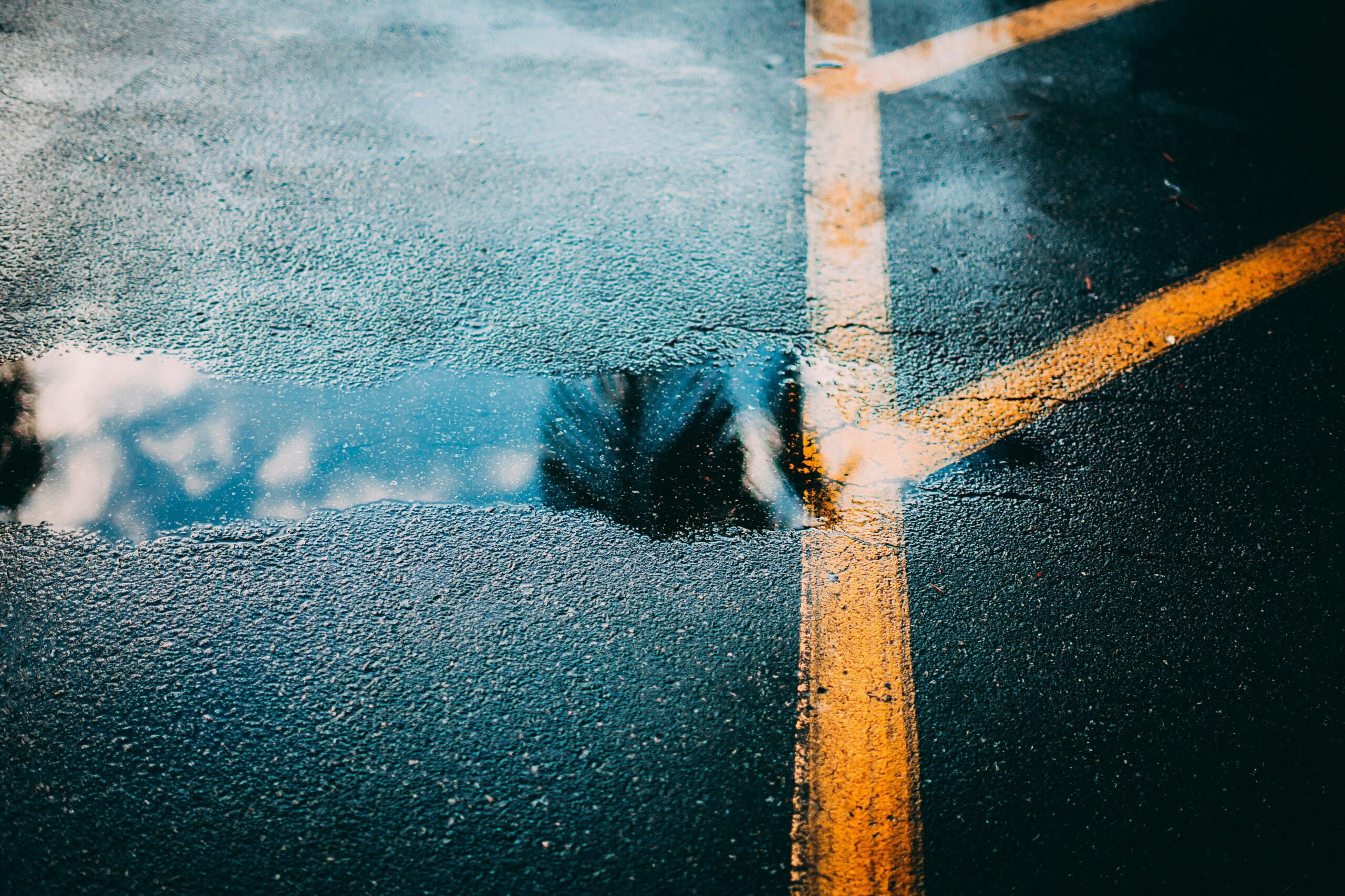 EN: Reflection of the sky in a puddle on asphalt, symbolizing seeing the familiar in a new way. KR: 아스팔트 위 물웅덩이에 비친 하늘, 익숙한 것 속에서 새로운 시선을 상징한다.