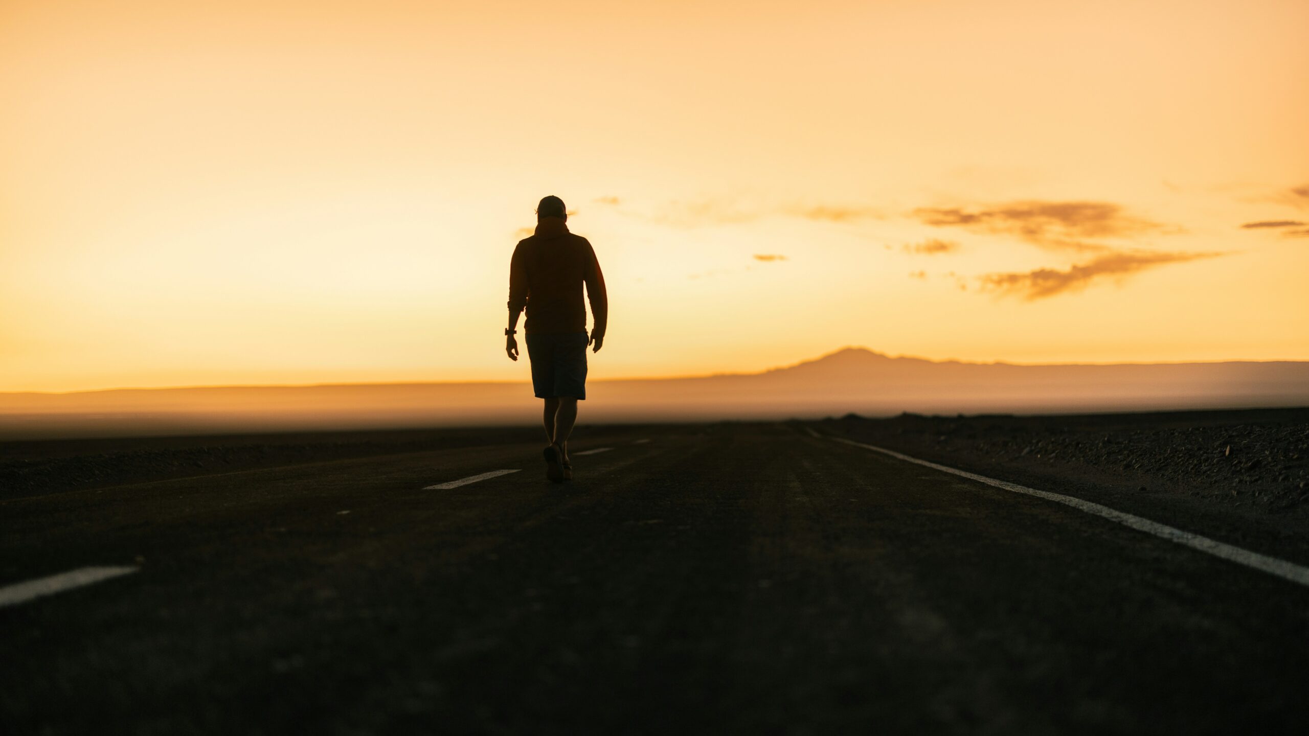 EN: A solitary person walking along an empty road at sunset, symbolizing the journey of choosing one’s own path. KR: 노을 속 텅 빈 도로를 혼자 걸어가는 사람의 모습, 자신의 길을 선택하는 여정을 상징하는 장면