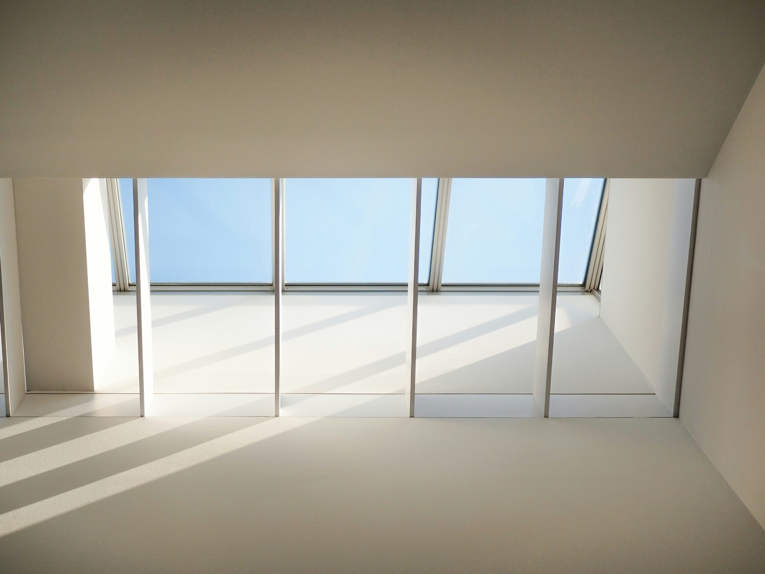 EN Soft sunlight entering through a minimalist window, casting calm shadows on a white wall KR 미니멀한 실내 공간의 창문으로 들어오는 부드러운 햇빛과 고요한 그림자